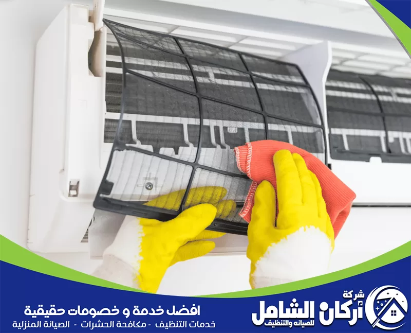 روائح كريهة واحتمال نمو العفن 0500073610 شركة أركان الشامل فني ينظف فلتر مكيف سبليت بقطعة قماش بعد إخراجه من الجهاز، في صورة توضح خطوة تنظيف الفلاتر لإزالة الغبار وتحسين كفاءة التبريد.
