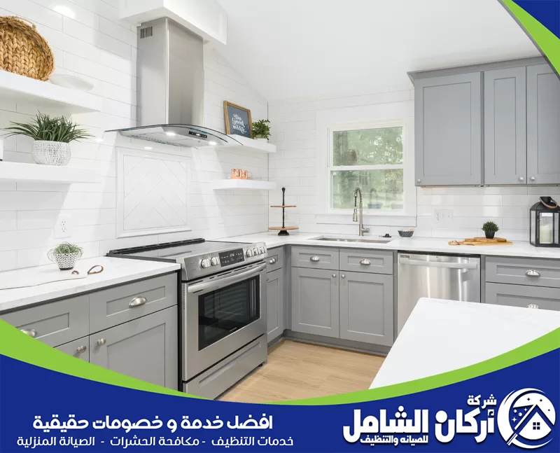 تنظيف دهون المطبخ 0500073610 اركان الشامل مطبخ بأثاث أبيض وأجهزة ستانلس ستيل، يظهر نظافة وترتيب المكان بشكل جيد.