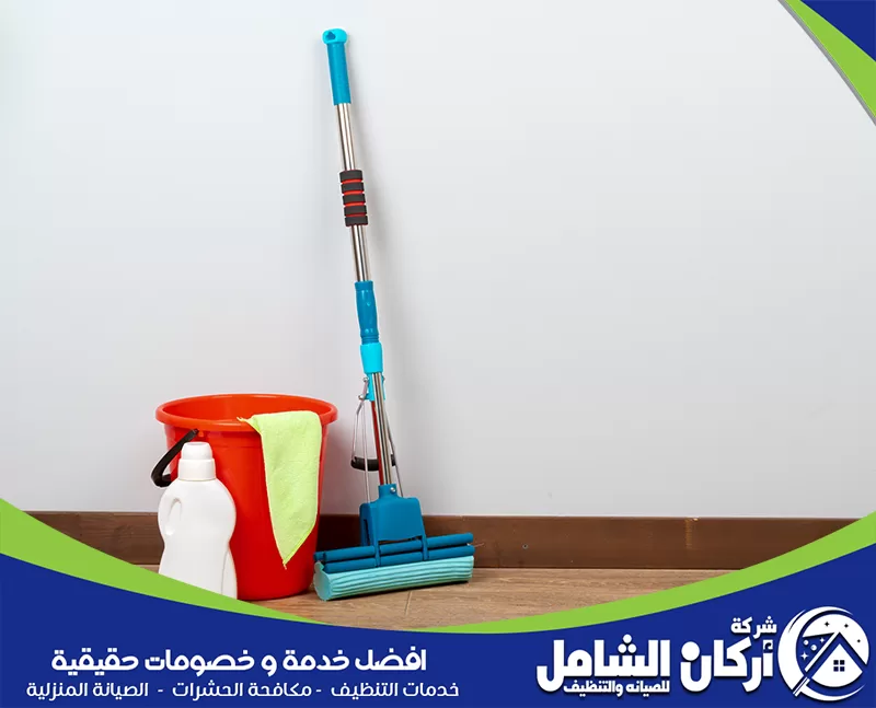 تنظيف الصالة والمجلس ضمن جدول البيت 0500073610 أركان الشامل. دلو وممسحة على أرضية خشبية، في سياق مقال عن جدول تنظيف البيت اليومي والأسبوعي والشهري.