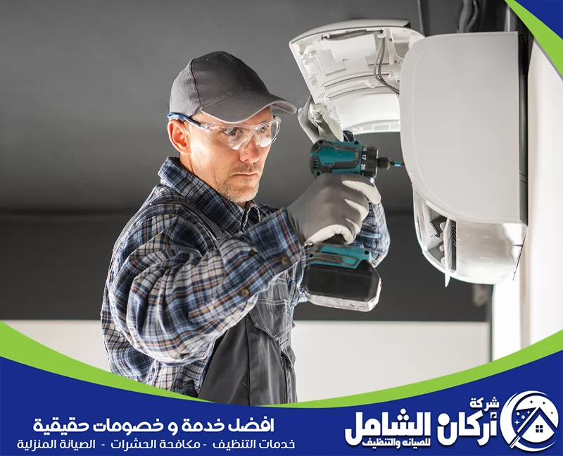 تمديد نحاس مكيفات بالقطيف 0500073610 شركة أركان الشامل رجل يرتدي خوذة ونظارات يعمل على إصلاح مكيف في شركة فك وتركيب مكيفات بالقطيف.