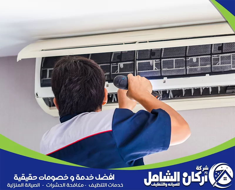 فك وتركيب مكيفات شباك بالاحساء 0500073610 شركة أركان الشامل رجل يقوم بإصلاح مكيف هواء في الأحساء، مع التركيز على تفاصيل التركيب والتفكيك.