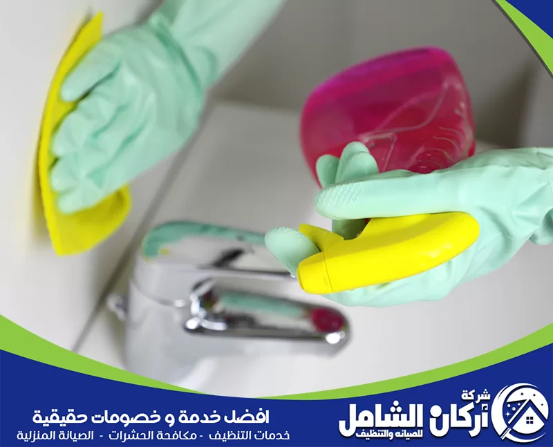 التخلص من رائحة الحمام الكريهة 0500073610 أركان الشامل شخص يرتدي قفازات ينظف حوض الحمام باستخدام إسفنجة صفراء.