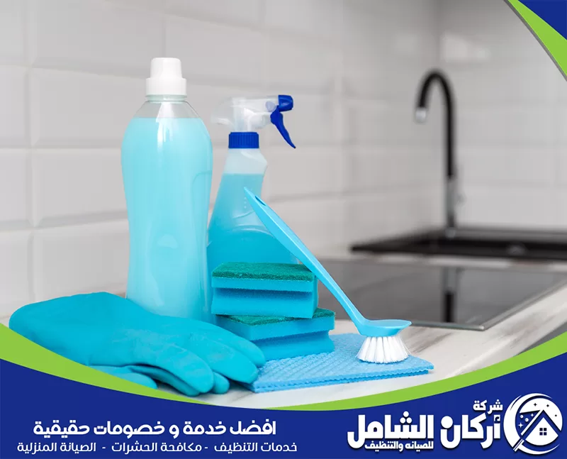 إزالة الدهون وتجفيف الأسطح 0500073610 اركان الشامل مطبخ يحتوي على مواد تنظيف وزجاجة ماء، يُظهر طريقة تنظيف وترتيب المطبخ بشكل فعال.