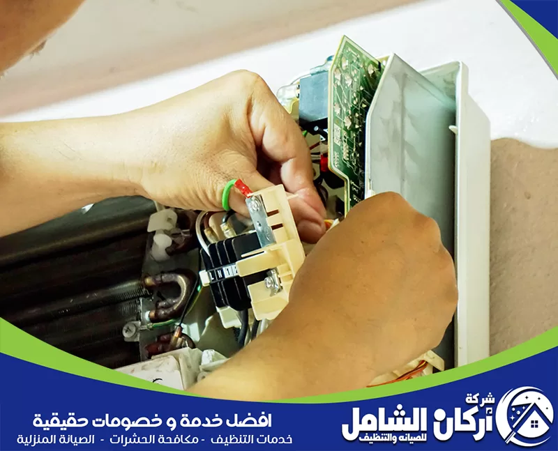 صيانة مكيفات شباك بجدة 0500073610 شركة اركان الشامل. رجل يقوم بإصلاح مكيف باستخدام مفك براغي، مع التركيز على تفاصيل العمل.